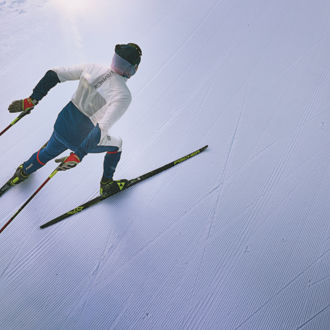 Ein Skifahrer fährt auf einer perfekt präparierten Piste. Die klare, schneebedeckte Umgebung strahlt Ruhe und Konzentration aus.