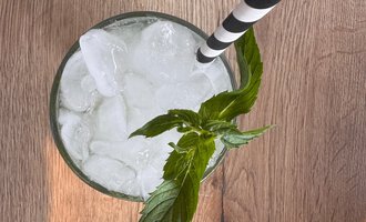 A refreshing drink with ice and fresh mint leaves. The straw is black and white striped. | © MORE VIBES by Alex Lambsdorff