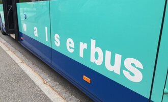 A green and blue bus with the inscription "walserbus". The surface is smooth and modernly designed. | © Kleinwalsertal Tourismus