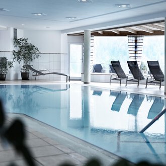 Ein heller Innenpool mit Liegen und Pflanzen. Der Raum ist modern und einladend gestaltet. | © Hotel Birkenhöhe