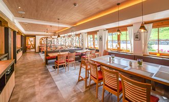 A modern restaurant with wooden furniture and an inviting atmosphere. Large windows let in plenty of daylight and offer a view of the outside. | © Familienhotel Kleinwalsertal Hotelgesellschaft mbH