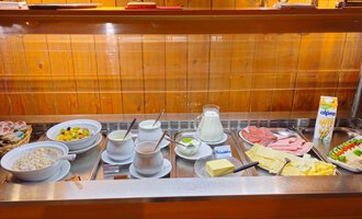 Ein reichhaltiges Frühstücksbuffet mit verschiedenen Käsesorten, Aufschnitt, Joghurt, Müsli und frischem Obst. Dazu gibt es Milch und Säfte. | © Hotel Garni Adler | Mennel&Feurstein Immo Invest GmbH