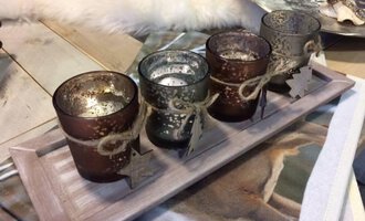 A decorative candle holder with four tealights in different colors. The holders are adorned with jute and small stars. | © HUIMWEA Alpendekor