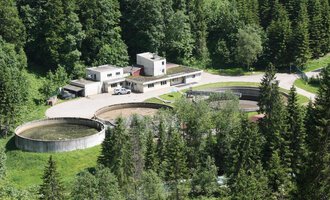 Eine moderne Kläranlage umgeben von dichtem Wald. Es gibt mehrere große runde Becken und ein Verwaltungsgebäude. | © Gemeinde Mittelberg