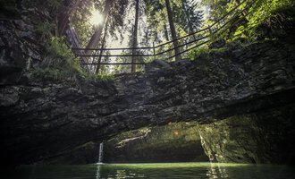 Ein idyllischer Ort mit klaren Gewässern und steilen Felsen. Im Hintergrund sind hohe Bäume und ein Sonnenstrahl sichtbar. | © Kleinwalsertal Tourismus | Oliver Farys