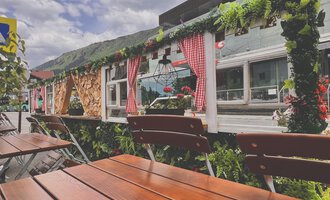A cozy café decorated with plants and flowers. The outdoor terrace features wooden tables and an inviting atmosphere. | © Riezlern Eck | Sead Sulejmani