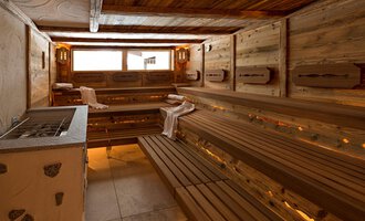 A modern sauna with wooden benches and gentle lighting. The room design creates a relaxing atmosphere. | © Aparthotel Kleinwalsertal Haller GmbH & Co KG