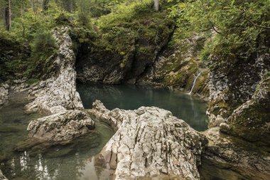 Ste rocks and a peaceful waterfall in the Black Forest, surrounded by green trees in autumn. | © Kleinwalsertal Tourismus eGen • Photographer: Andre Tappe