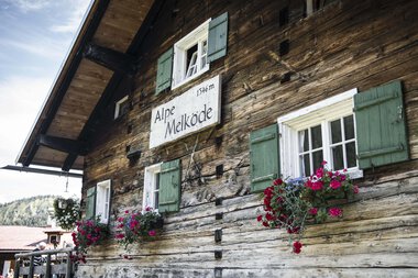 Wooden house with green shutters and flower boxes, sign 'Alpe Melköde', in the Black Forest | © Kleinwalsertal Tourismus eGen • Photographer: Andre Tappe