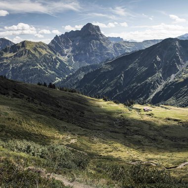 Weitblick auf grüne Berge und Täler im Schwarzwald mit Bergen im Hintergrund an einem sonnigen Tag. | © Kleinwalsertal Tourismus eGen • Fotograf: Andre Tappe
