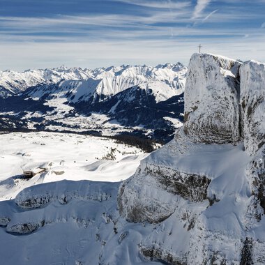 Berglandschaft mit schneebedeckten Gipfeln und Felsen, Blick über eine Winterlandschaft mit Bergen im Hintergrund. | © Kleinwalsertal Tourismus eGen • Fotograf: Bastian Morell
