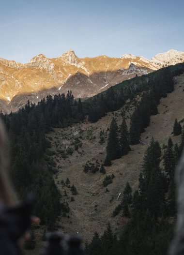 Two people looking at a mountain landscape with snow-capped peaks in the background while in nature. | © Kleinwalsertal Tourismus eGen • Photographer: Hannah Bichay