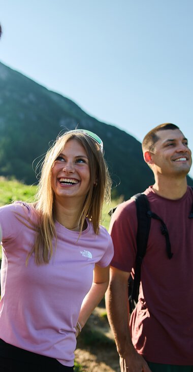 Three young adults hiking in the mountains, smiling and enjoying nature in Kleinwalsertal. | © Kleinwalsertal Tourismus eGen • Photographer: Oliver Farys