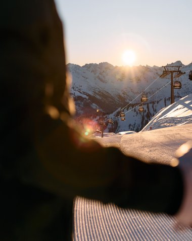 Alpine skier at sunset in Ifen, with mountain and chairlift in the background, during sunset. | © Kleinwalsertal Tourismus eGen • Photographer: Oliver Farys