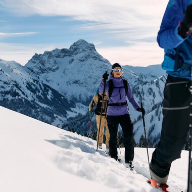 Gruppe von Skitourengehern unterwegs in verschneiter Berglandschaft im Kleinwalsertal, mit Rucksack und Skistöcken. | © Kleinwalsertal Tourismus eGen • Fotograf: Oliver Farys