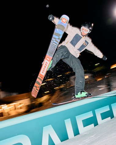 Man night skiing in Kleinwalsertal, jumping with skis over a barrier at night, illuminated by floodlights. | © Kleinwalsertal Tourismus eGen • Photographer: Oliver Farys