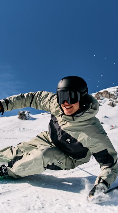 Skier in deep snow with a skier wearing a white ski suit, black helmet, under clear sky at Ski Alpin Ifen. | © Kleinwalsertal Tourismus eGen • Photographer: Oliver Farys