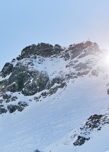 Snow-covered mountains in the Alps with sunshine, view of a rocky summit region in winter. | © Kleinwalsertal Tourismus eGen • Photographer: Oliver Farys