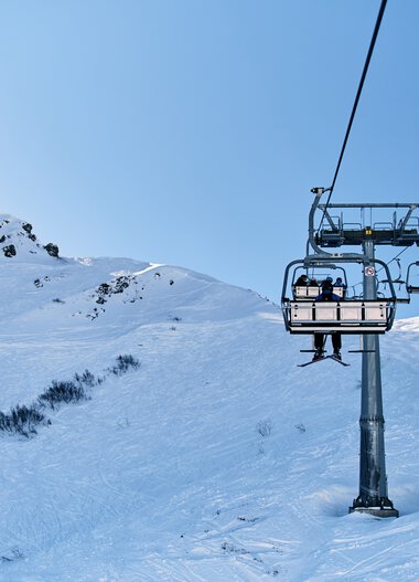 Skilift in einer verschneiten Berglandschaft mit blauem Himmel am Kleinwalsertal im Winter. | © Kleinwalsertal Tourismus eGen • Fotograf: Oliver Farys