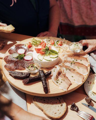 Bergbuffet mit Käse, Wurst, Brot und Aufschnitt bei einem Wandertag im Freien. | © Kleinwalsertal Tourismus eGen • Fotograf: Stefan Klauser 