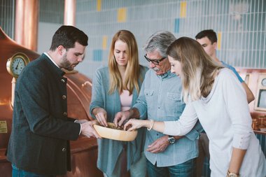 Tour of the Zoetler Brewery with several people examining and discussing a beer glass. | © Kleinwalsertal Tourismus eGen • Zötler Brauerei