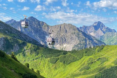 Sommerliche Kanzelwandbahn mit Gondeln im Alpenpanorama, grüne Hügel, Berge und blauer Himmel. | © Oberstdorf · Kleinwalsertal Bergbahnen