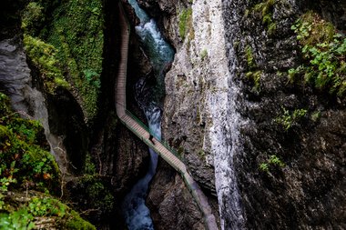 View from the Zwingsteig trail into the Breitach Gorge in summer, narrow gorge with water and rocks, surrounded by green vegetation. | © Kleinwalsertal Tourismus eGen • Breitachklamm • Photographer: Domink Berchtold