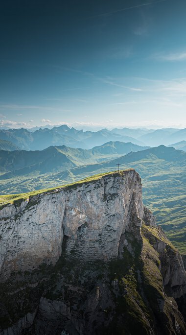 Mountain landscape with green hills and steep cliffs under a blue sky, taken from the Ifen. | © Kleinwalsertal Tourismus eGen • Photographer: Robert Niederwolfsgruber