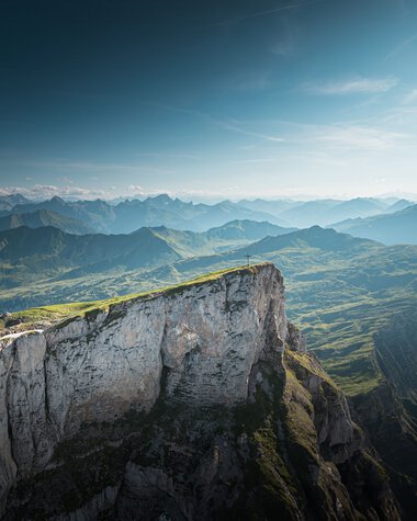 Mountain landscape with green hills and steep cliffs under a blue sky, taken from the Ifen. | © Kleinwalsertal Tourismus eGen • Photographer: Robert Niederwolfsgruber