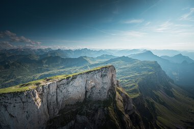Mountain landscape with green hills and steep cliffs under a blue sky, taken from the Ifen. | © Kleinwalsertal Tourismus eGen • Photographer: Robert Niederwolfsgruber
