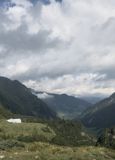 Berglandschaft mit Tal, bewölktem Himmel und grünen Hügeln in den Bergen. | © Kleinwalsertal Tourismus eGen • Fotograf: Antje Pabst