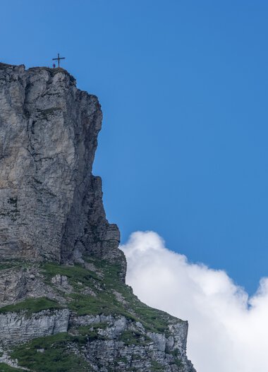 Cliff at the summit of Ifen with cross, under a blue sky with clouds in summer. | © Kleinwalsertal Tourismus eGen • Photographer: Steffen Berschin