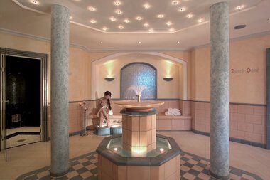 Innenraum eines Wellnesshotels mit einer Wasserfontäne in der Mitte, Wasserbecken und ruhiger Atmosphäre. | © Hotel Birkenhöhe